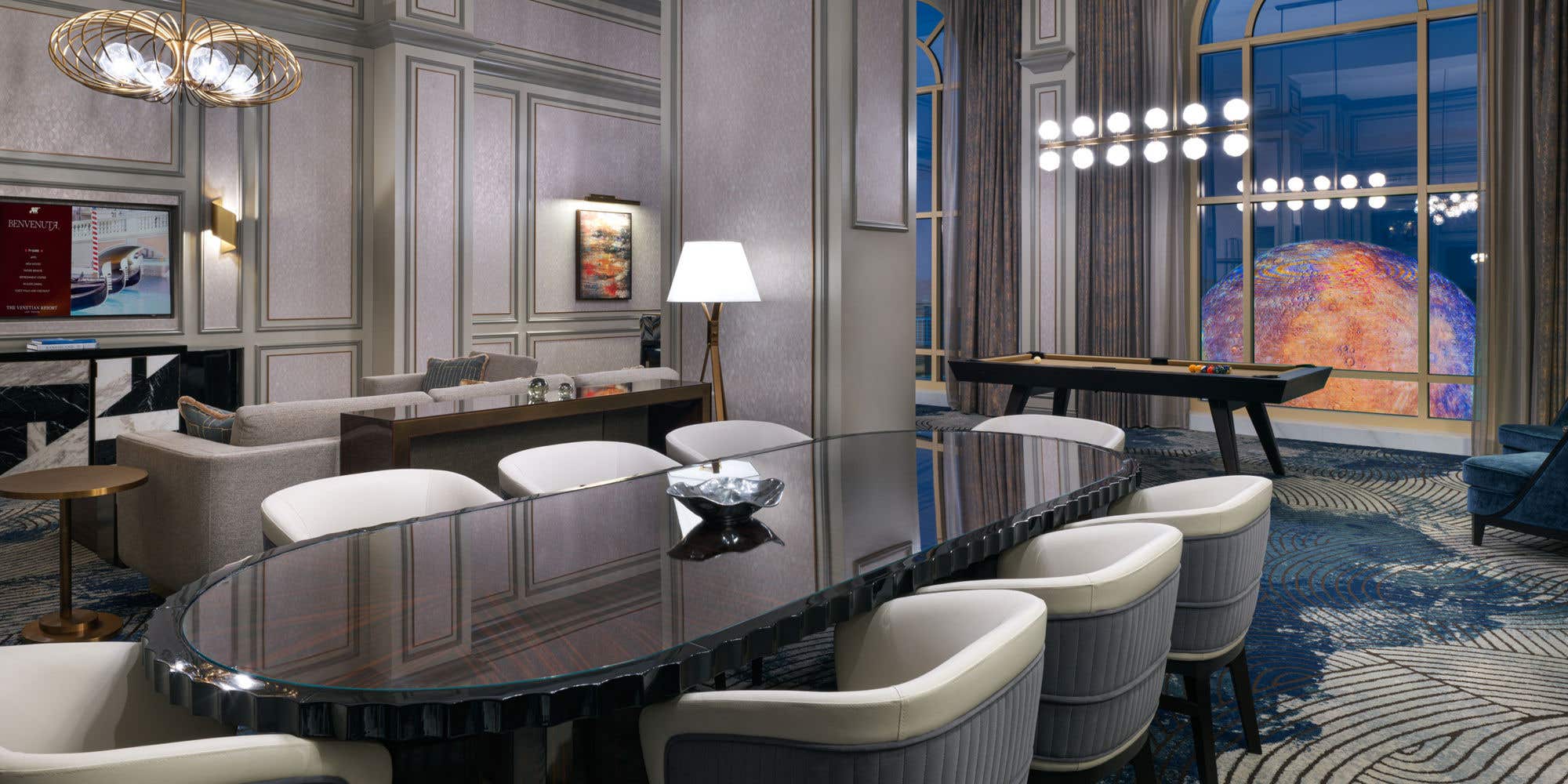 A modern living room with a dining table, seating, and a pool table in a Corner Two Bedroom Suite.