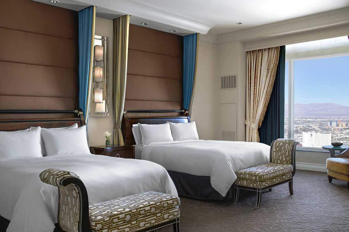 A hotel room with two Queen beds and a large window overlooking the city.